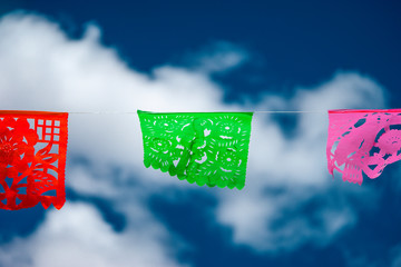 Tradicional decoración de papeles picados bajo un cielo azul.