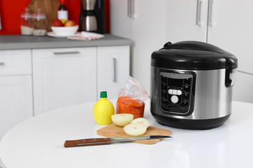 New modern multi cooker and products on table in kitchen. Space for text
