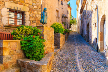 Fototapeta na wymiar Narrow street with stone houses in old town in Tossa de Mar, Costa Brava, Spain