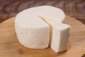 Fototapeta na wymiar Slice of Ricotta Cheese over a wooden board