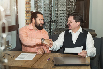 Handshake. Two business men agreed together. Partners. Signing financial documents sitting at the table in the office.