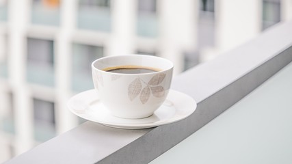 Porcelain cup of black coffee on a windows background. Coffee in the big city. 16:9 panoramic format. Copy space