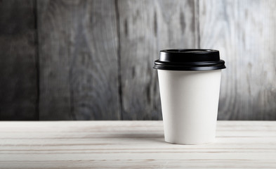 Close up of hot black coffee paper cup on on wooden table