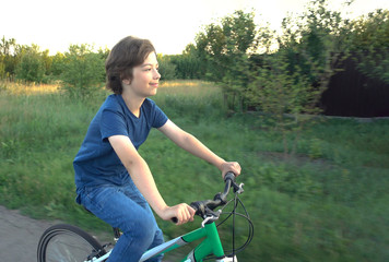 Obraz premium teenager riding a bicycle on the road summer sunlit