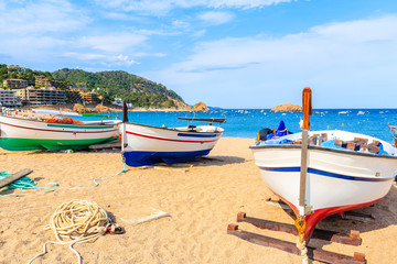 Fishing boats on golden sand beach in Tossa de Mar town, Costa Brava, Spain