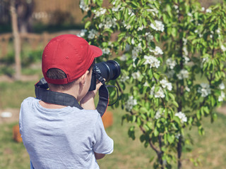 Fototapeta premium Obtaining new skills. Cute European boy is taking shoots in the garden.