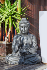 Statue of a meditating Buddha on a background of tropical greenery.