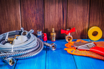 Plumbing supplies and tools on a blue wooden background close-up.