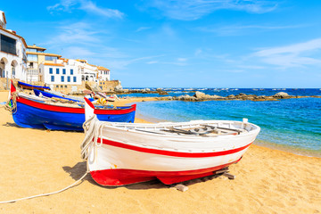 Fototapeta na wymiar Traditional fishing boat on beach in Calella de Palafrugell, scenic village with white houses and sandy beach with clear blue water, Costa Brava, Catalonia, Spain