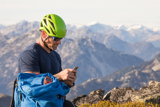 A climber sends a safety message using his smartphone from summit.