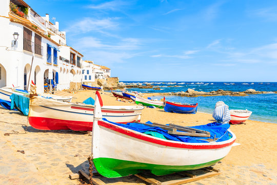 Traditional fishing boats on beach in Calella de Palafrugell, scenic village with white houses and sandy beach with clear blue water, Costa Brava, Catalonia, Spain