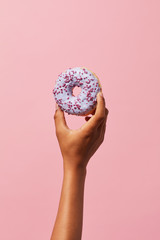 Fototapeta na wymiar Closeup of unrecognizable African-American kid holding single glazed donut against pink background, copy space