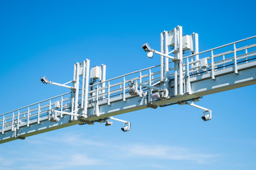 Overhead highway speed cameras on an arch of metal. Traffic cameras over the motorway on a blue sky background. 
