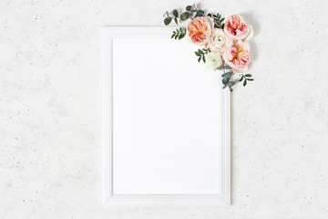 Wedding, birthday sign board mock-up scene. Vertical white wooden frame. Decorative floral corner. Eucalyptus, pink English roses and ranunculus flowers. Concrete table background. Flat lay, top view.