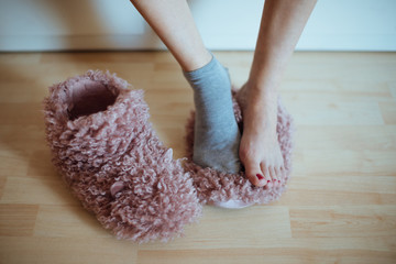 Early cold morning wake up! Woman's feet  standing on one (of two) home plush slippers - woman...
