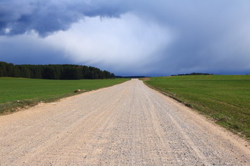 gravel road in the middle of the field, before a thunderstorm