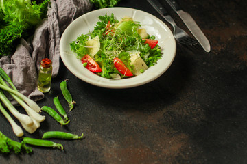 salad with tomato, lettuce, arugula, spinach and other leaves. food background. top