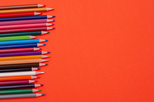 Color pencils on red-orange background.Close up.