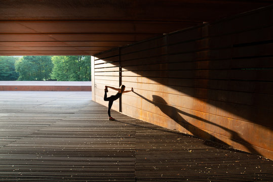 young woman stretching after running and leaning in a amazing geometrical building