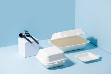 Compostable sugarcane containers and cornstarch cutlery over blue background - obrazy, fototapety, plakaty