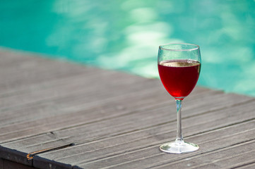 Red wine in a glass on water swimpool background