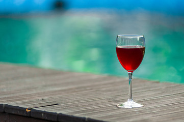 Red wine in a glass on water swimpool background