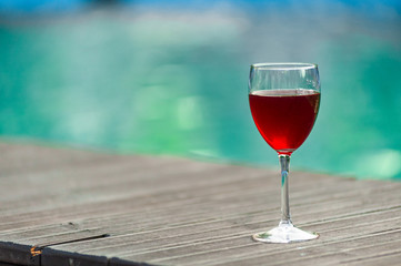 Red wine in a glass on water swimpool background