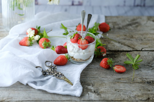 Creamy sweet dessert with fresh juicy tasty strawberries served inside a glass on a rustic wooden table