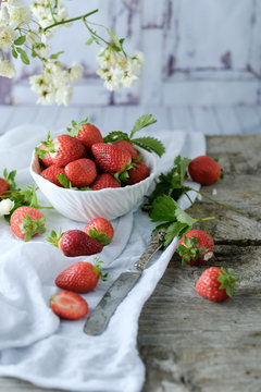 Creamy sweet dessert with fresh juicy tasty strawberries served inside a glass on a rustic wooden table