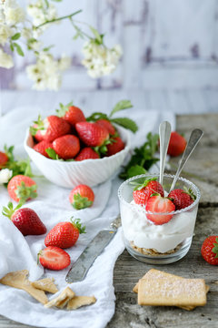 Creamy sweet dessert with fresh juicy tasty strawberries served inside a glass on a rustic wooden table