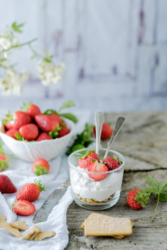 Creamy sweet dessert with fresh juicy tasty strawberries served inside a glass on a rustic wooden table