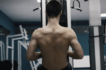 Very power athletic guy bodybuilder, execute exercise with gym apparatus, on broadest muscle of back