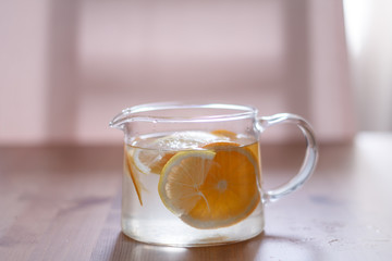 pitcher with lemonade and water sliced oranges and lemon on wooden table and coral and blue table background close up with blurred background