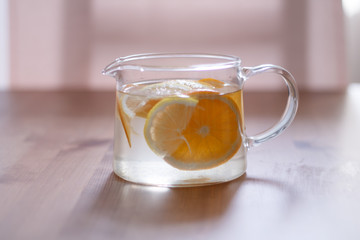 pitcher with lemonade and water sliced oranges and lemon on wooden table and coral and blue table background close up with blurred background