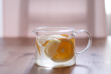 pitcher with lemonade and water sliced oranges and lemon on wooden table and coral and blue table background close up with blurred background