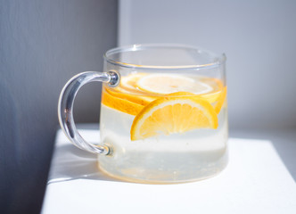 pitcher with lemonade and water sliced oranges and lemon on white table close-up with blurred background
