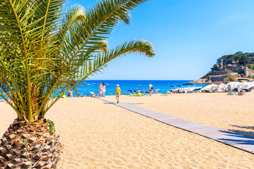 TOSSA DE MAR, SPAIN - JUN 3, 2019: People walking on sandy beach in Tossa de Mar town, Costa Brava,...