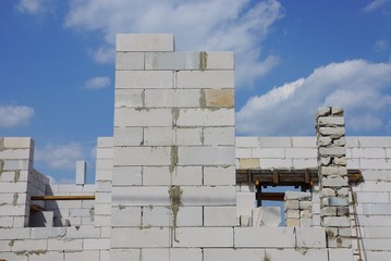 Obraz premium wall of an unfinished house of white bricks against the sky and clouds