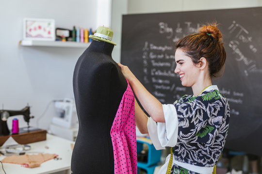 Teenage girl student practicing sewing on modern machine in cozy workshop
