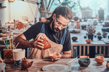 Fototapeta Diligent man is putting colourful clay to his new handmade pot. obraz