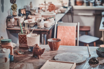 Empty bright workplace of clay potter with many different tools and dishes.