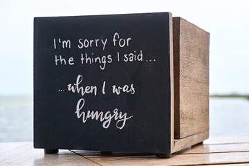 Wooden box in a restaurant with text or quote. I'm sorry for the things I said, when I was hungry 