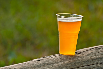 Beer in a plastic glass close-up. Alcoholic beverage at the festival. Bakal on a wooden board.