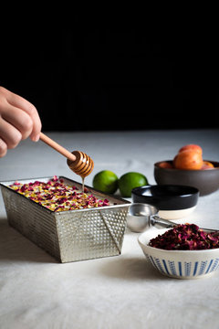 Hands of anonymous female putting container with delicious cheesecake on table near limes and honey with spices
