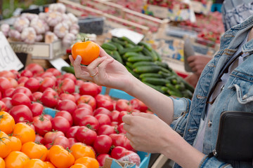 Young woman buying vegetables on stall at the local farmer's market