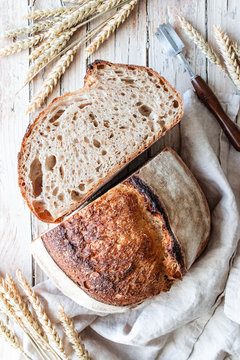 From above homemade fresh sourdough bread in tablecloth on wooden table