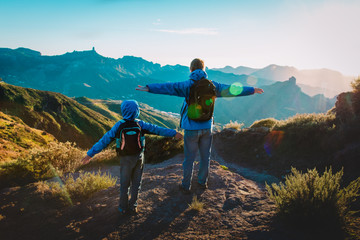 Happy father and son hiking at sunset mountains