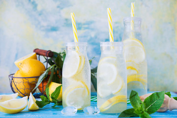 Cold refreshing drink with lemon and mint. Delicious summer lemonade with ice in the bottles.