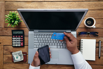 Plakat Man holding credit card and using laptop computer. Online Shopping Concept