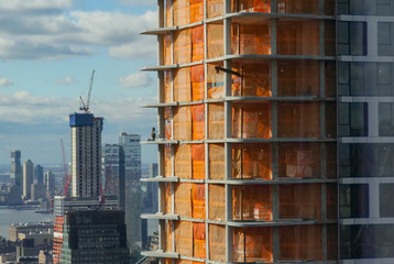 Unrecognizable worker kneeling while working on a skyscraper under construction.